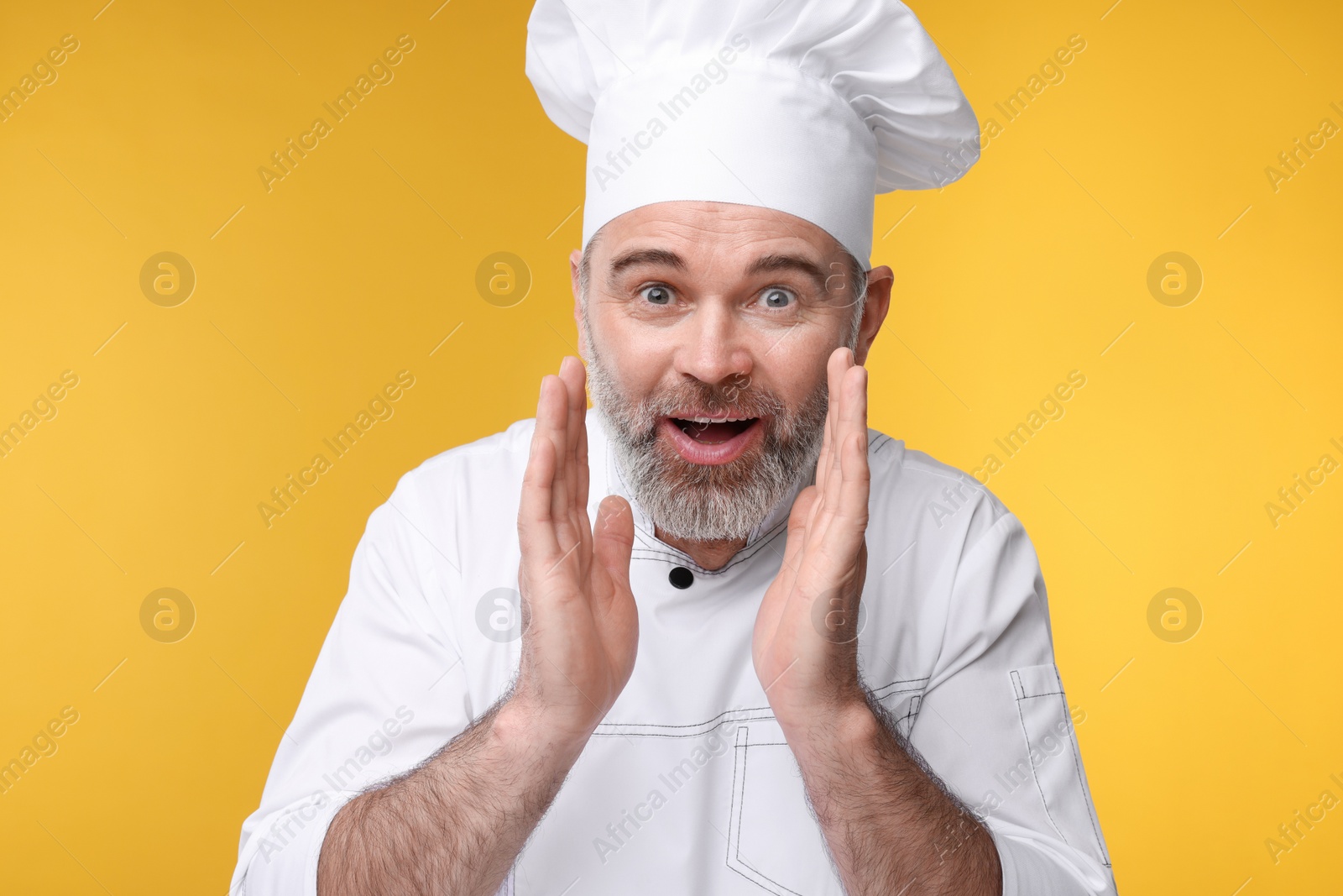 Photo of Surprised chef in uniform on orange background