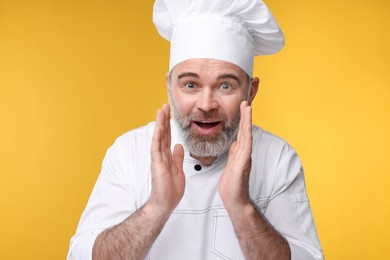 Surprised chef in uniform on orange background
