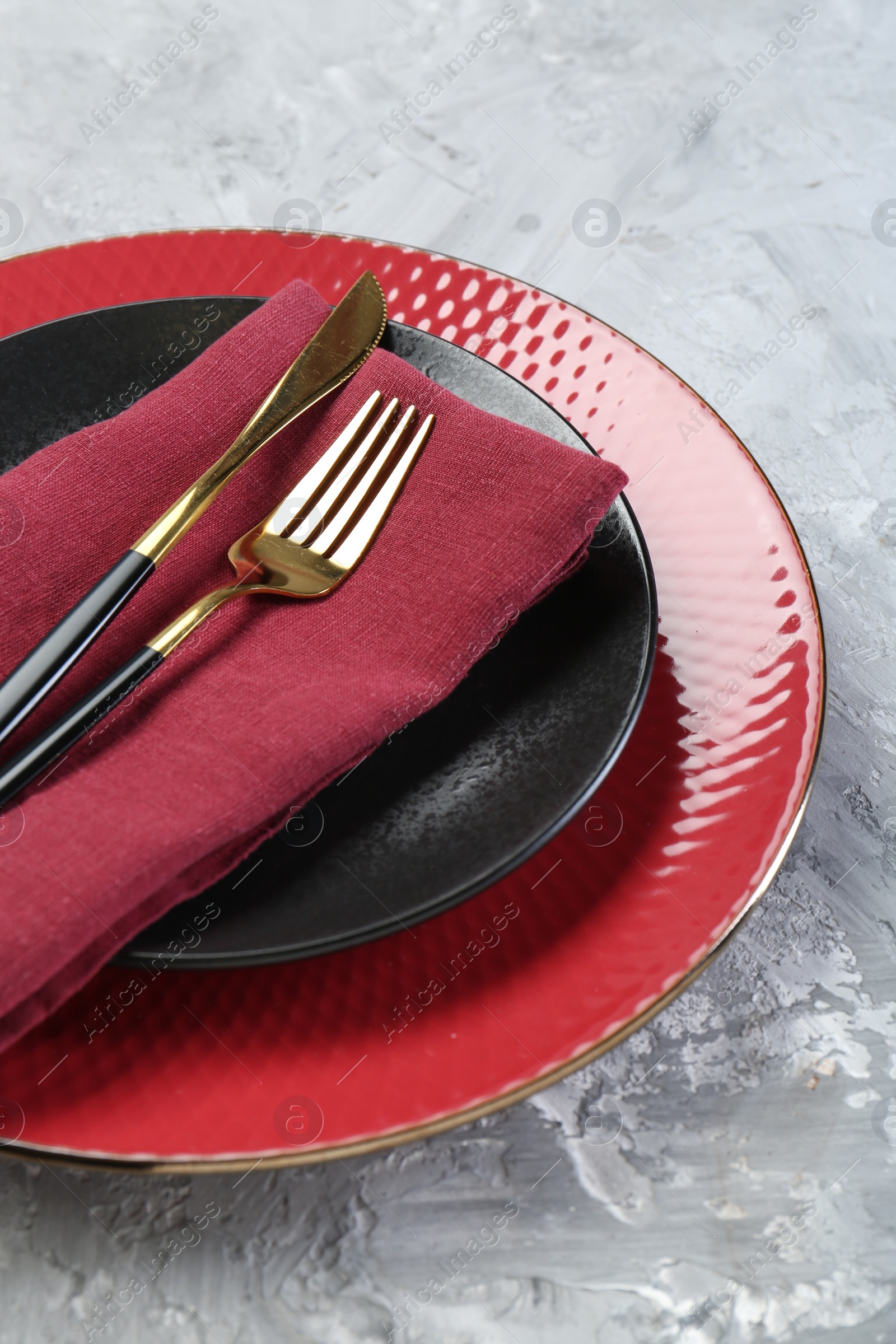 Photo of Clean plates, cutlery and napkin on gray table, closeup