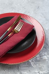 Clean plates, cutlery and napkin on gray table, closeup
