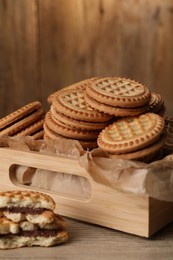 Photo of Tasty sandwich cookies with cream on wooden table, closeup