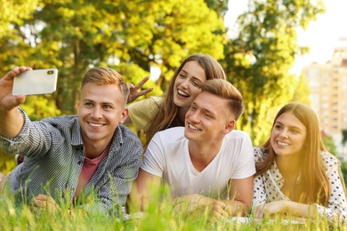 Photo of Young people taking selfie while having picnic in park on summer day