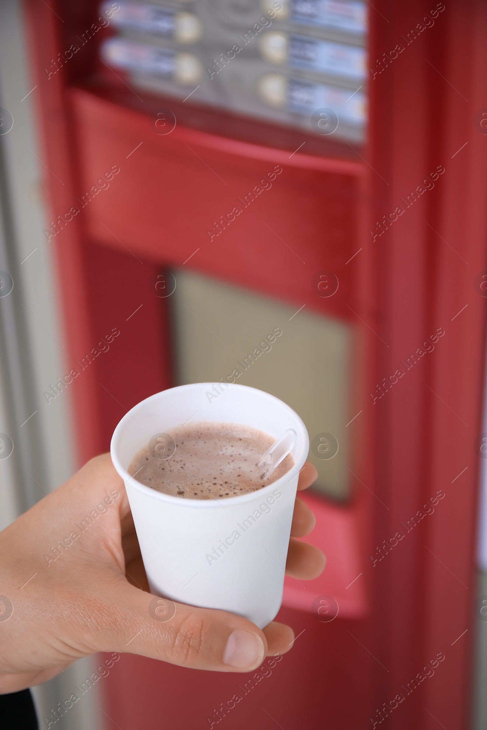 Photo of Woman holding paper cup with coffee near vending machine, closeup