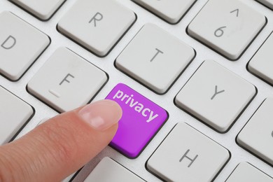 Woman pressing purple button with word Privacy on keyboard, closeup