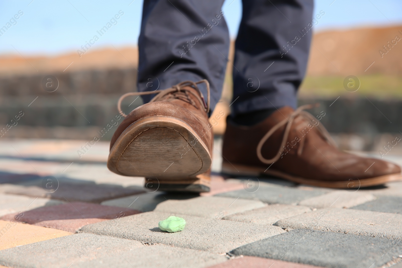 Photo of Man stepping in chewing gum on sidewalk. Concept of stickiness