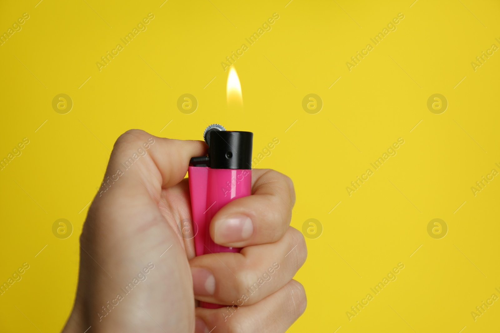 Photo of Woman holding pink lighter on yellow background, closeup. Space for text