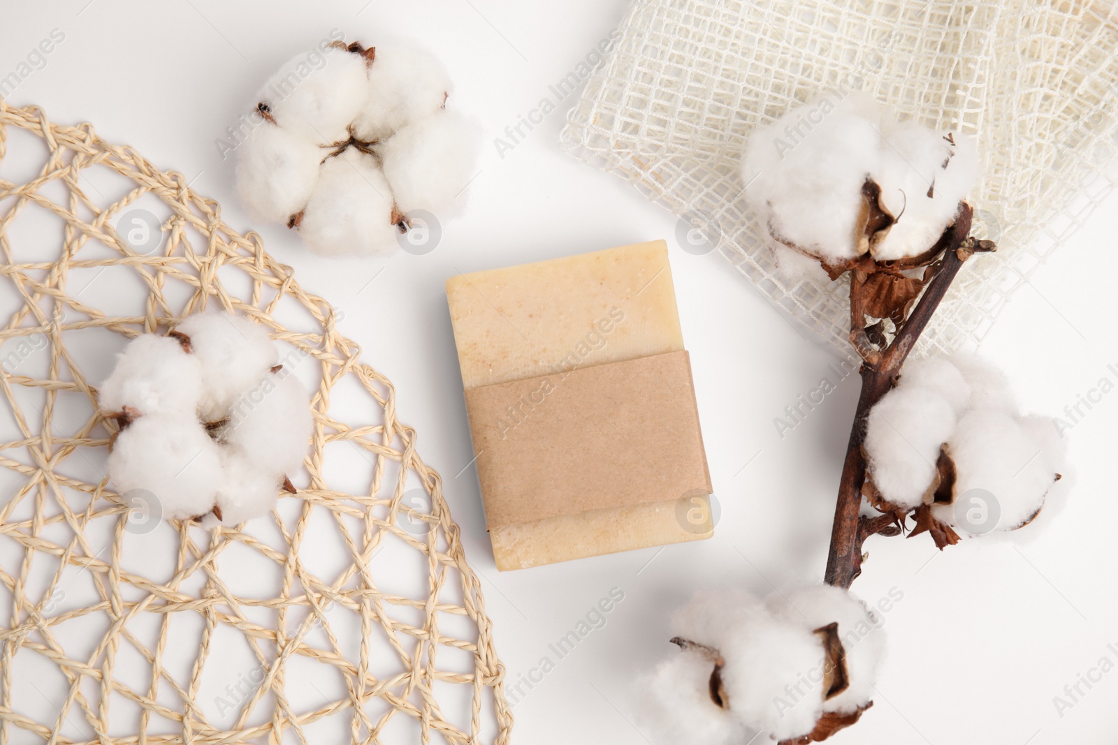 Photo of Soap bar and cotton flowers on white background, flat lay. Eco friendly personal care product