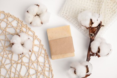 Photo of Soap bar and cotton flowers on white background, flat lay. Eco friendly personal care product