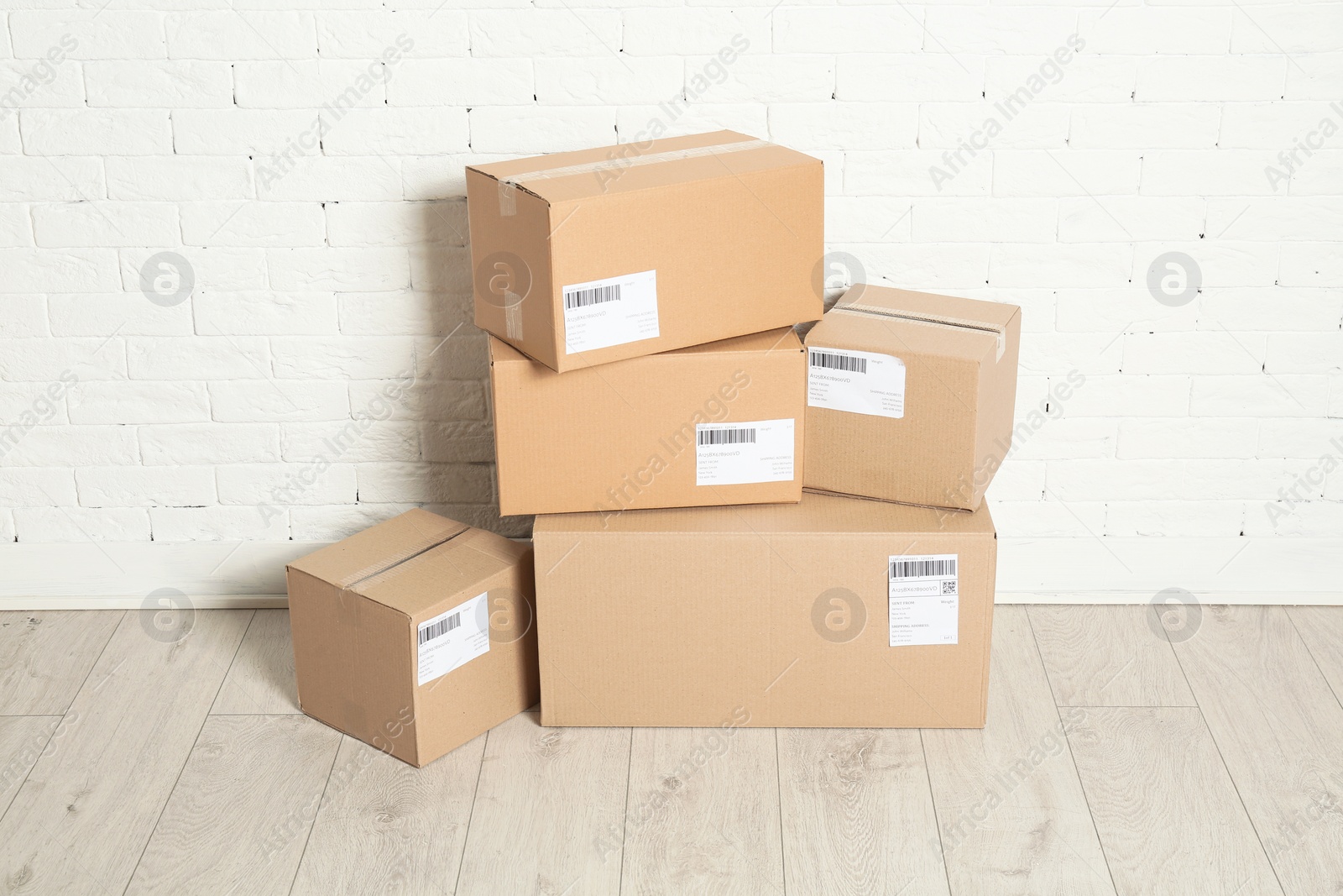 Photo of Stack of parcel boxes on floor against brick wall