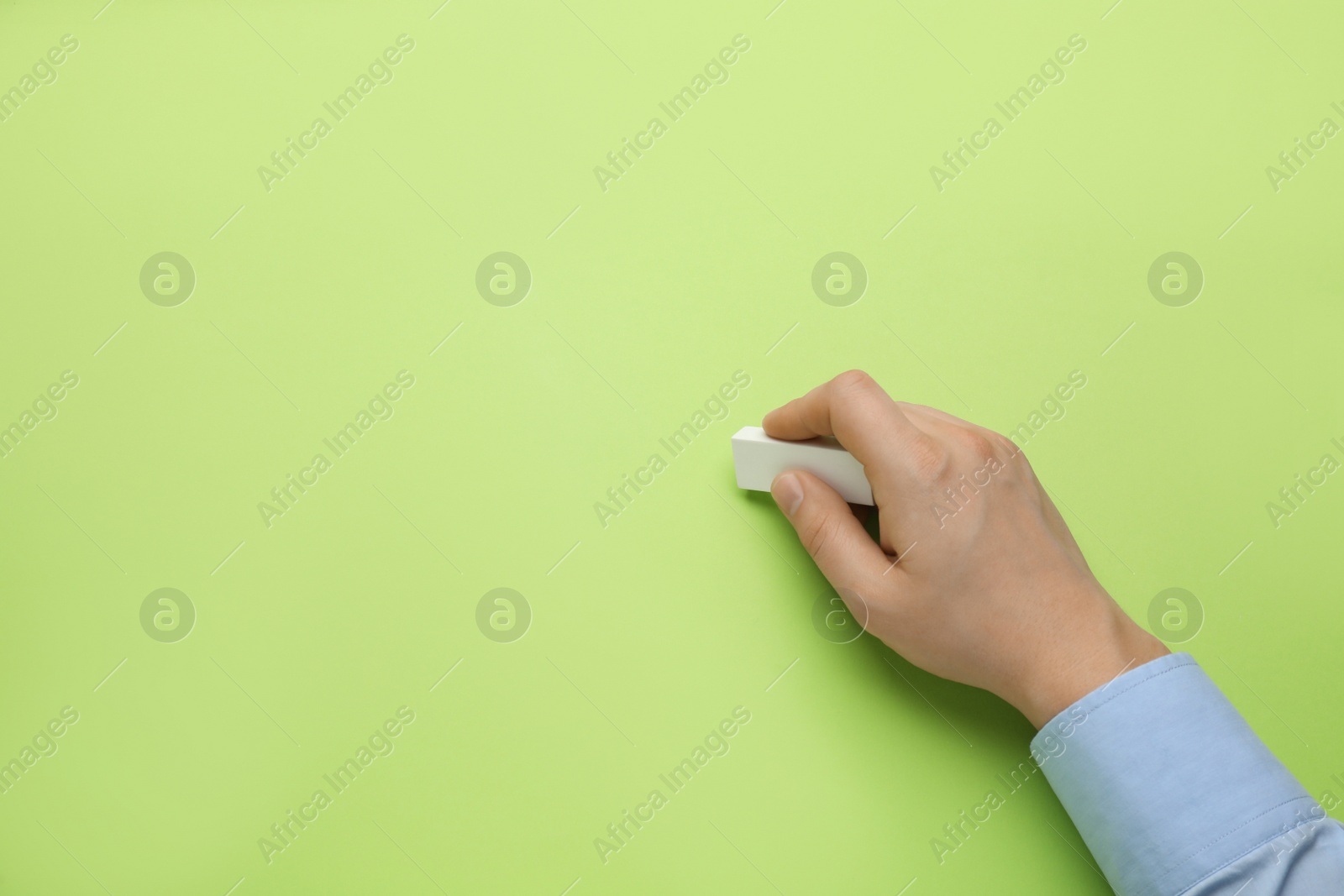 Photo of Man erasing something on green background, closeup. Space for text