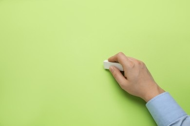 Photo of Man erasing something on green background, closeup. Space for text