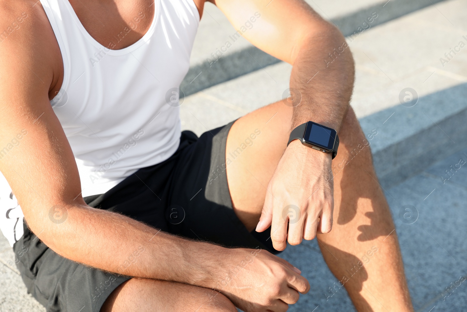 Photo of Man with fitness tracker after training outdoors, closeup