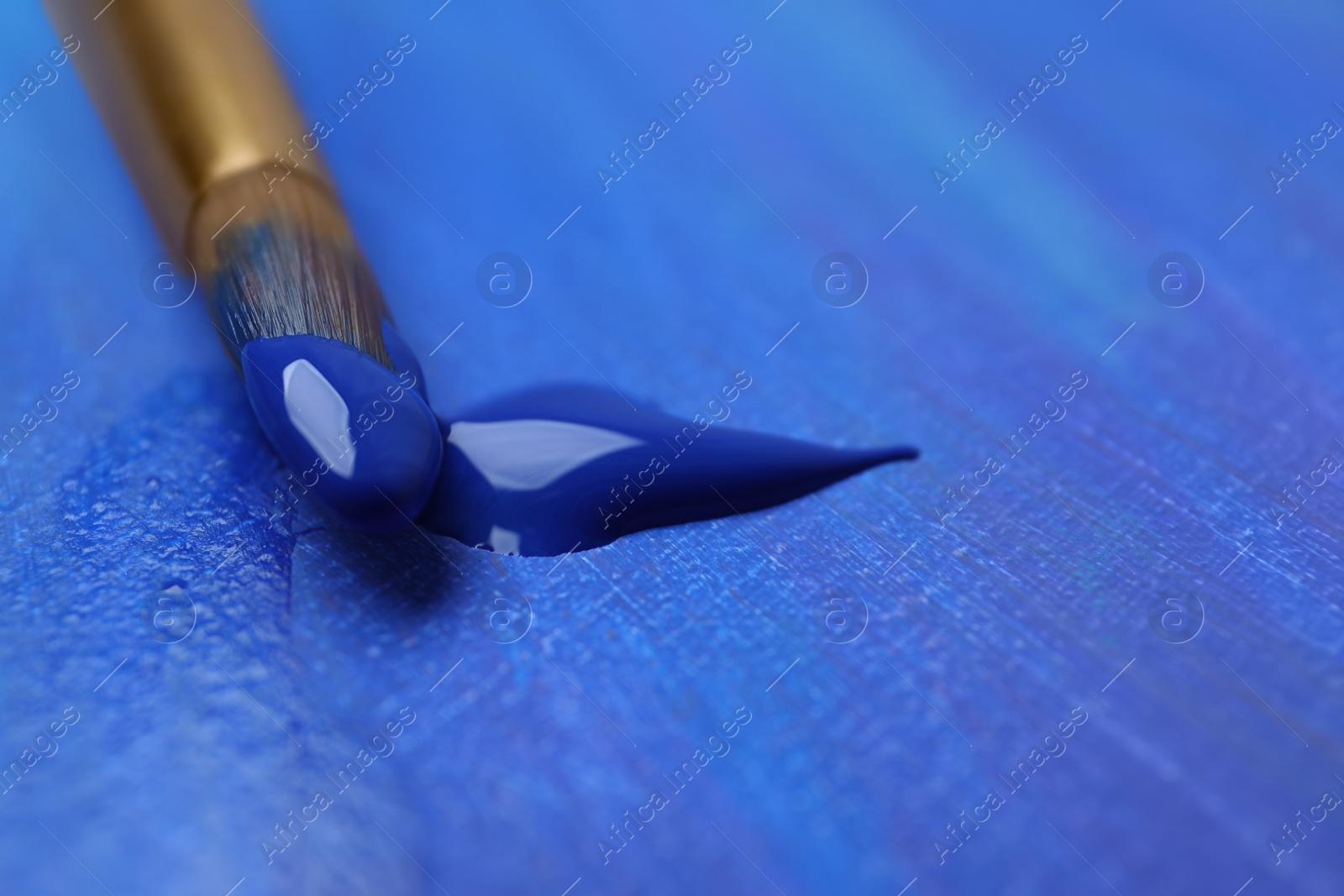 Photo of Brush with blue paint on abstract picture, closeup. Space for text