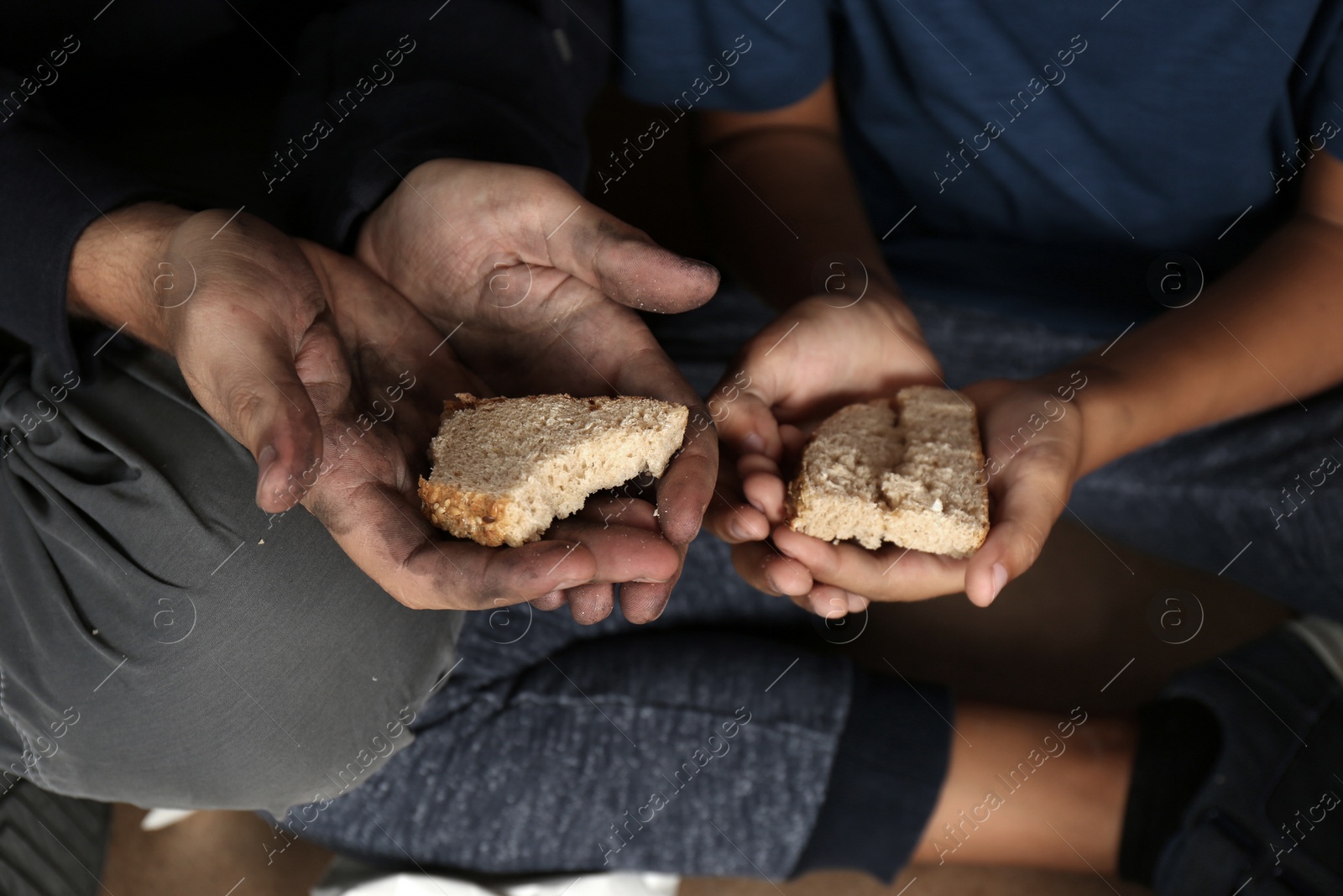 Photo of Poor man and his son holding bread, focus on hands