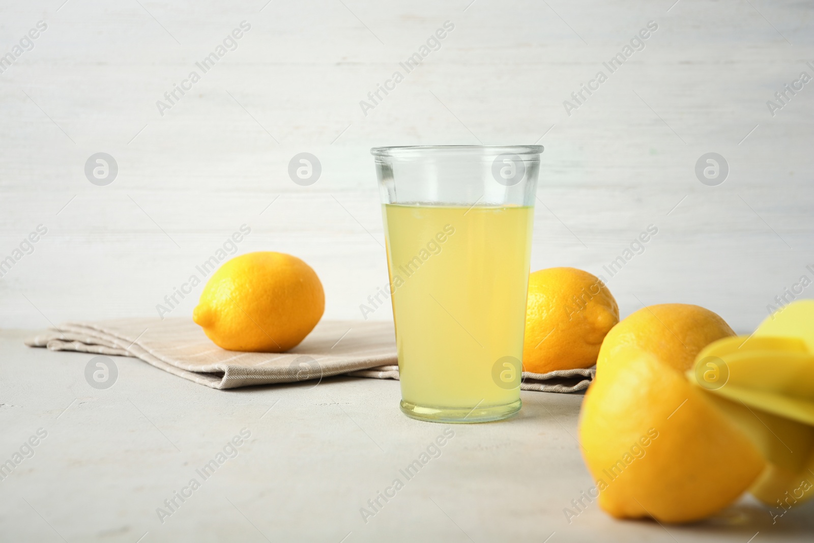 Photo of Glass with fresh lemon juice and fruits on table