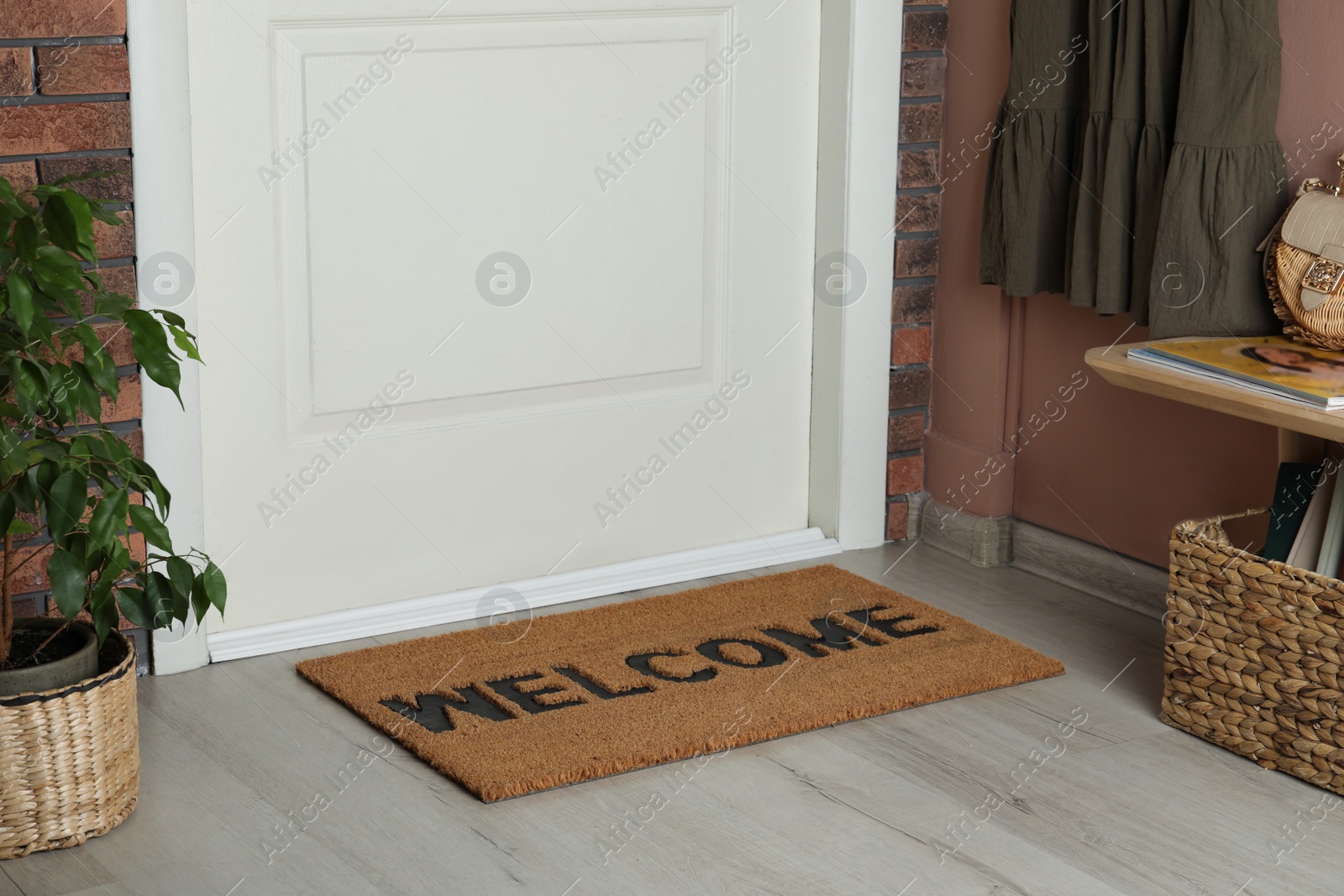 Photo of Door mat with word Welcome on wooden floor in hall