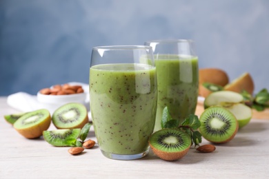 Photo of Delicious kiwi smoothie and ingredients on white wooden table