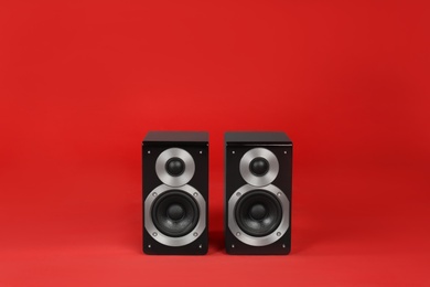 Photo of Modern powerful audio speakers on red background