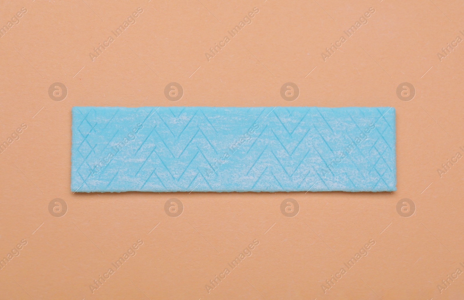 Photo of One stick of chewing gum on coral background, top view