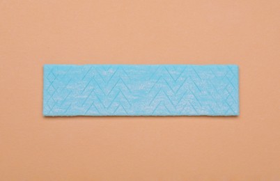 Photo of One stick of chewing gum on coral background, top view