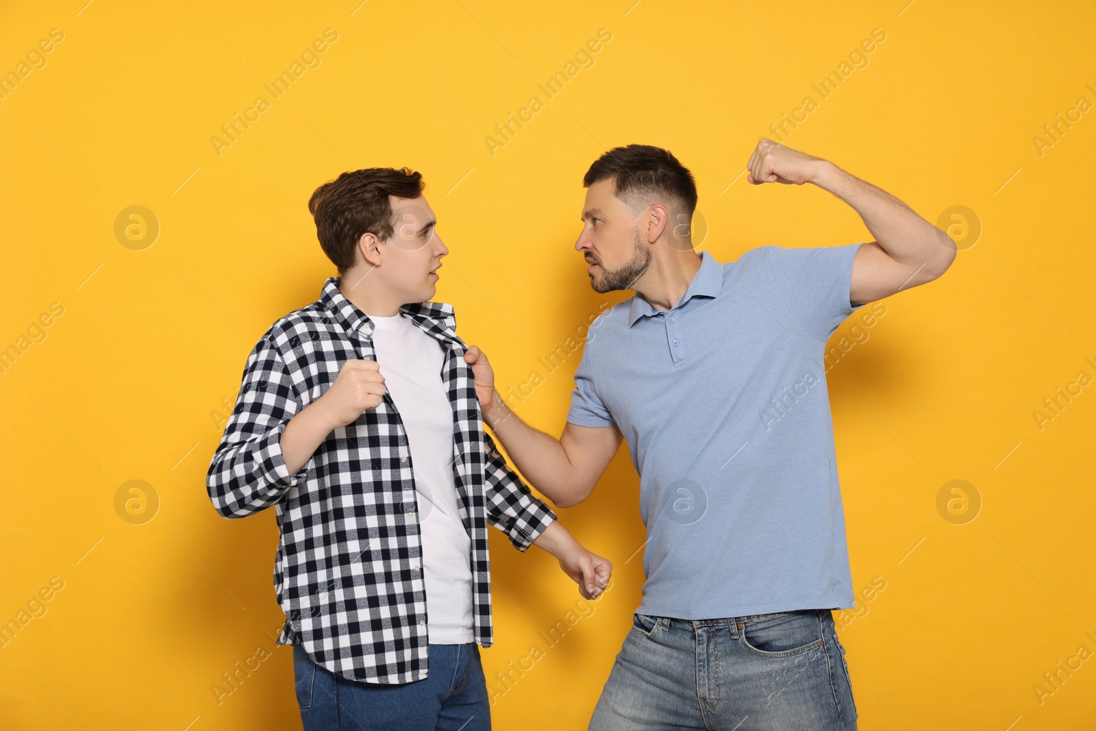 Photo of Two emotional men fighting on yellow background