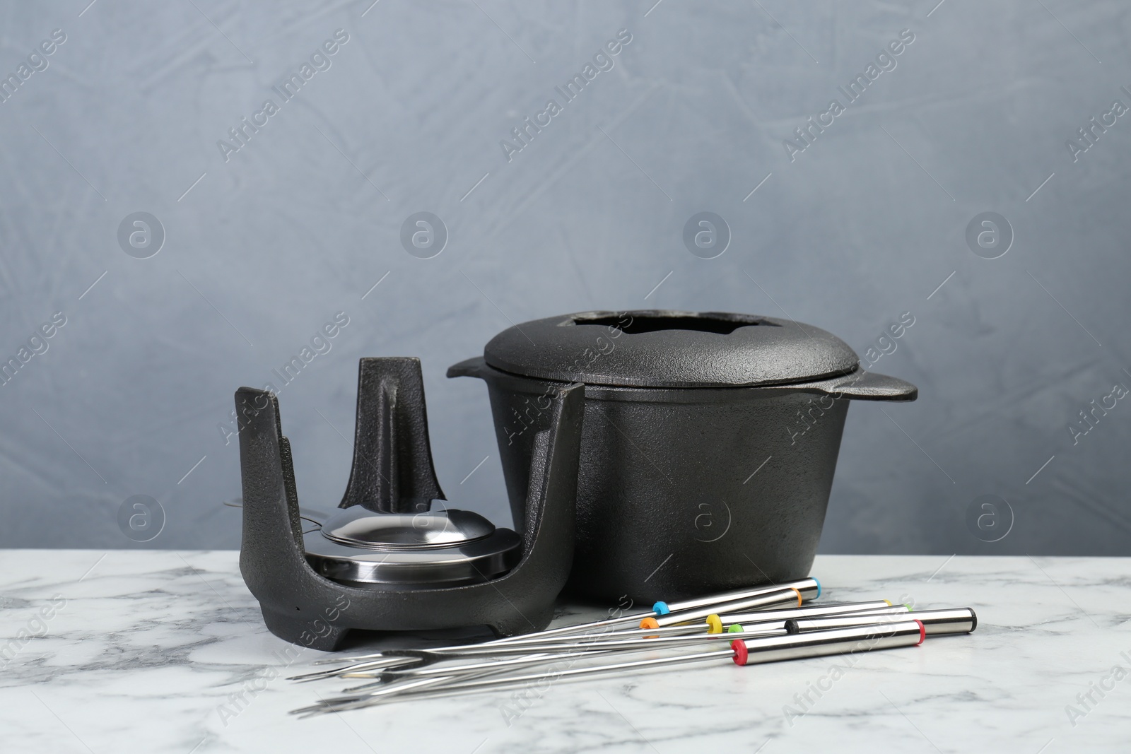 Photo of Fondue set on white marble table against light grey background