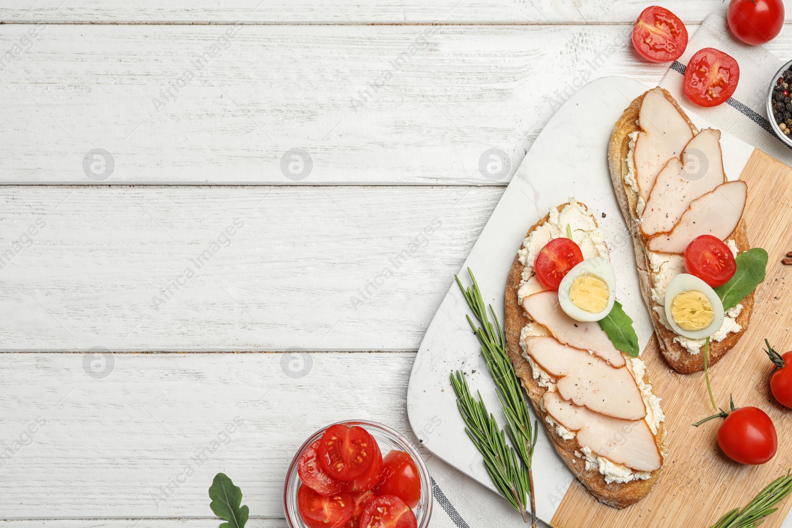 Photo of Board with delicious chicken bruschettas on white wooden table, flat lay. Space for text