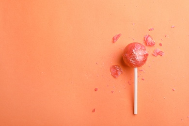 Photo of Broken coral lollipop and crumbs on color background. Space for text