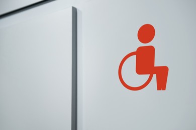 Image of Special needs accessible public toilet sign on white wall, closeup. Wheelchair symbol