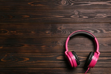 Photo of Stylish headphones on wooden background, top view. Space for text