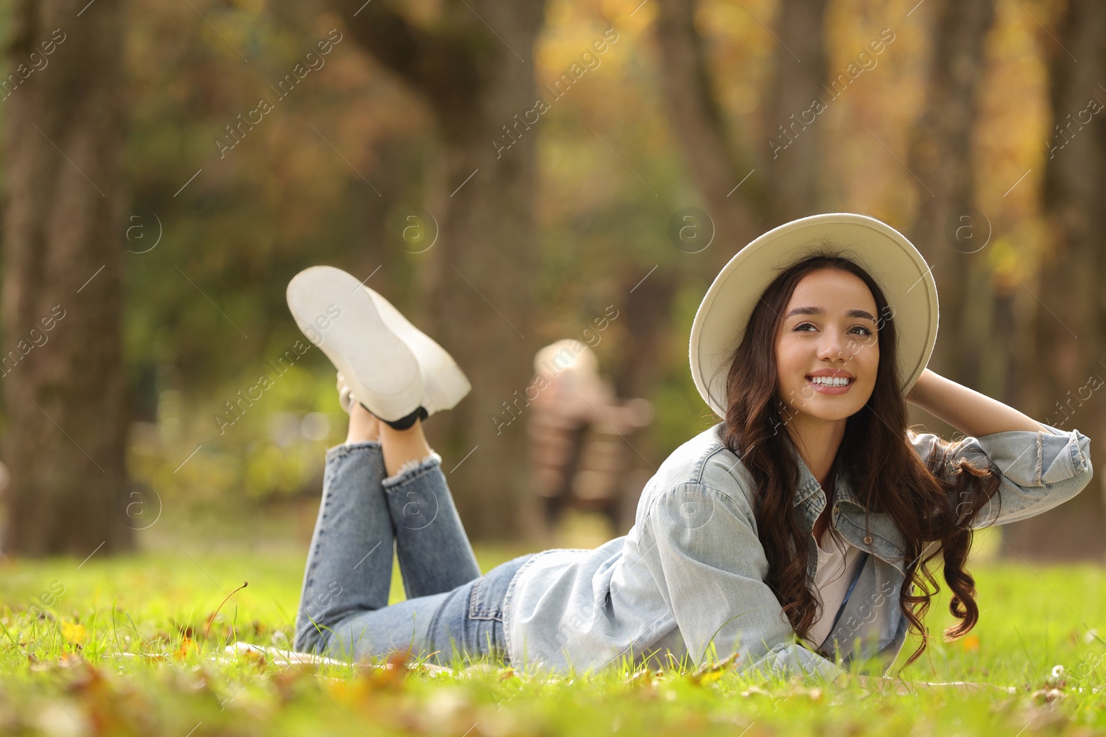 Photo of Young woman lying on green grass in park, space for text