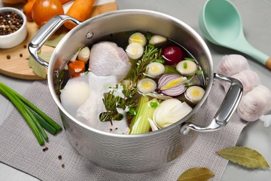 Photo of Pot and different ingredients for cooking tasty bouillon on light grey table