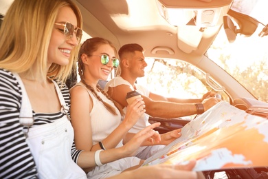 Photo of Happy friends with map in car on road trip