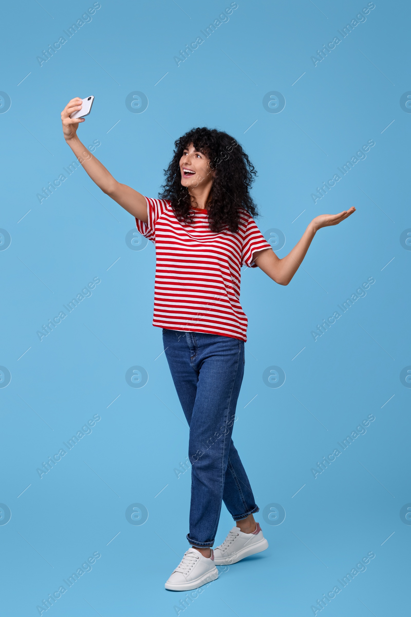 Photo of Beautiful young woman taking selfie on light blue background