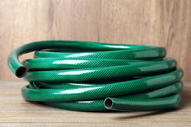 Photo of New green garden hose on wooden table