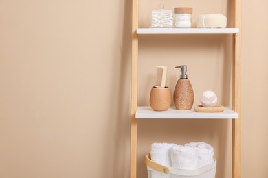 Photo of Different bath accessories and personal care products on shelving unit near beige wall, space for text