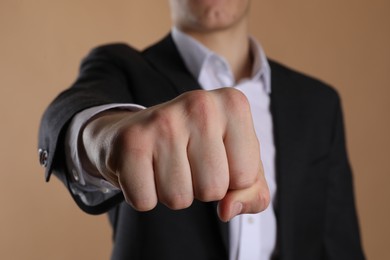 Photo of Businessman showing fist with space for tattoo on beige background, selective focus
