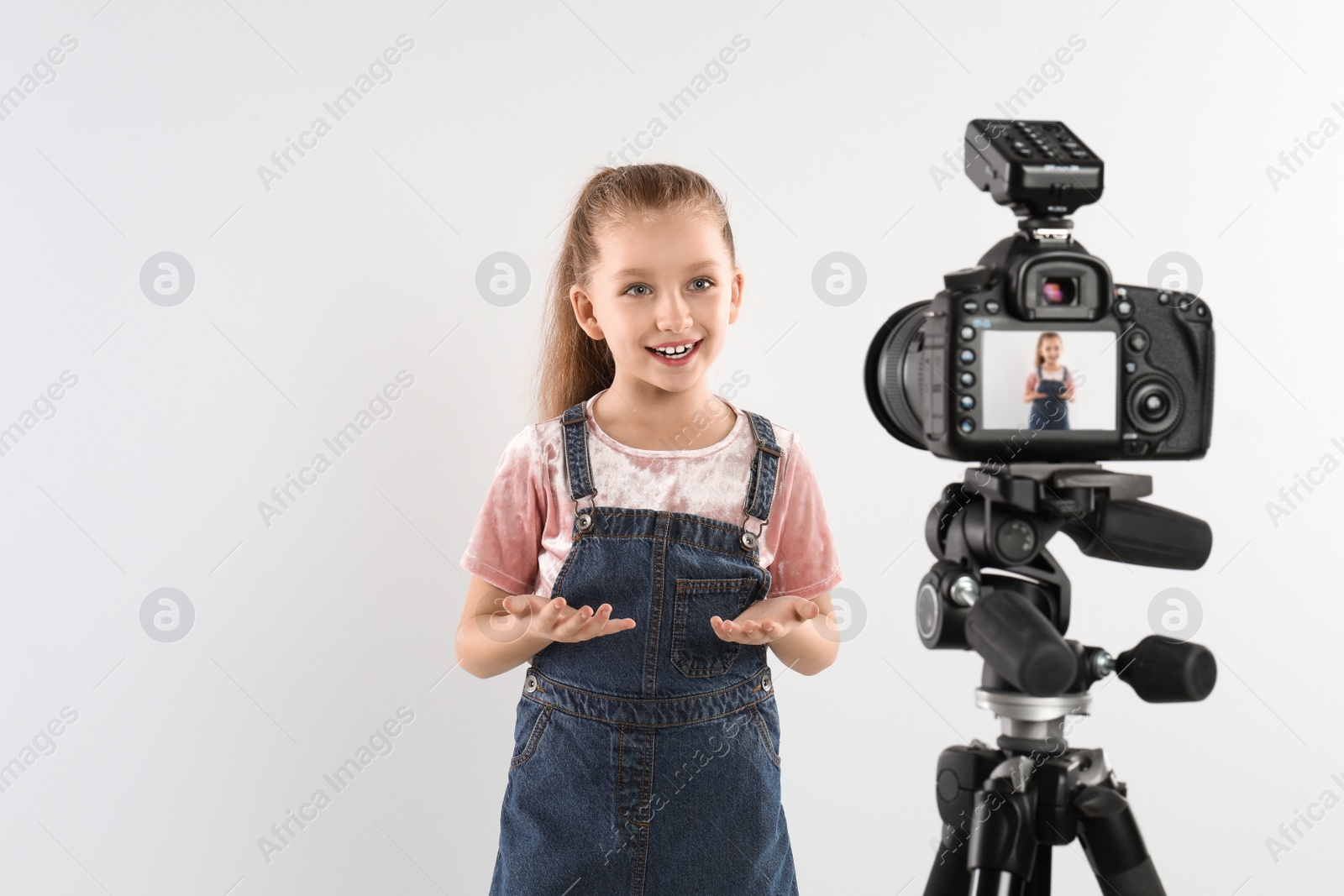 Photo of Cute little blogger recording video on white background