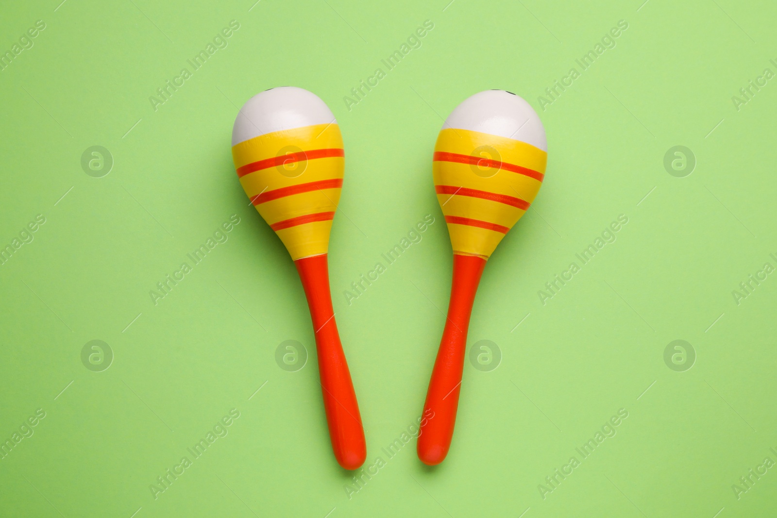 Photo of Colorful maracas on light green background, flat lay. Musical instrument