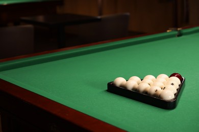 Billiard balls in triangle rack on green table indoors, space for text