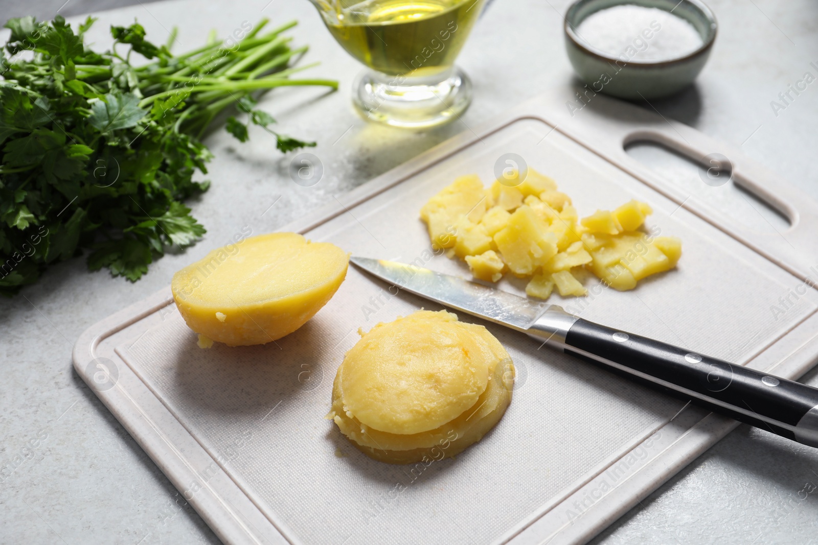 Photo of Cut boiled potatoes and ingredients on white table, closeup. Cooking vinaigrette salad