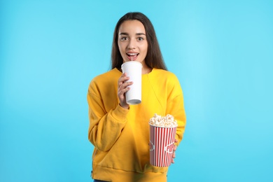 Photo of Woman with popcorn and beverage during cinema show on color background