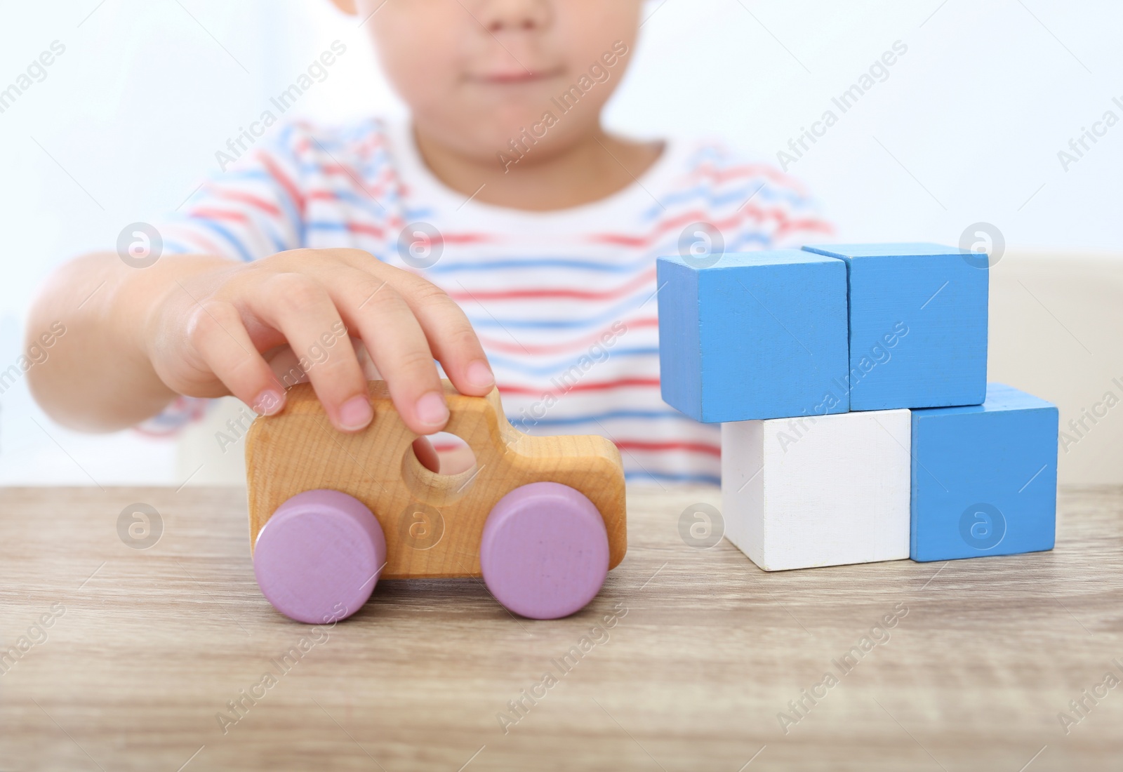 Photo of Little boy playing with toys at wooden table, closeup