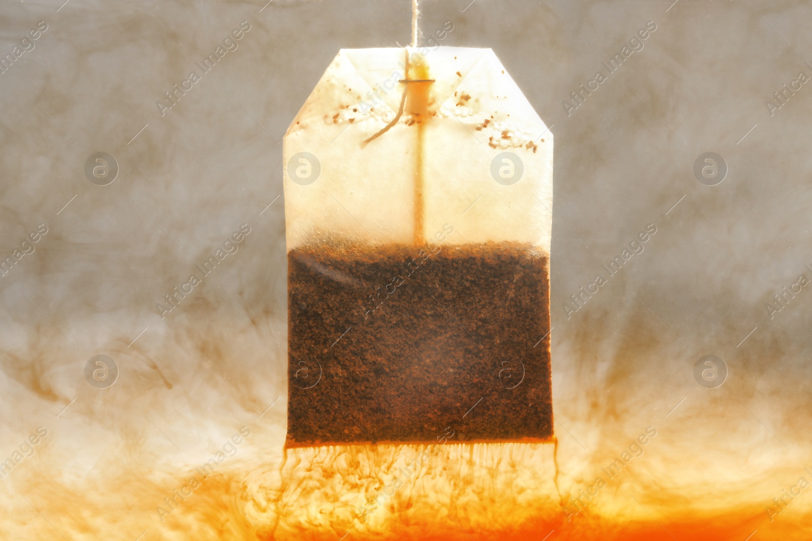 Photo of Brewing tea with bag in hot water, closeup