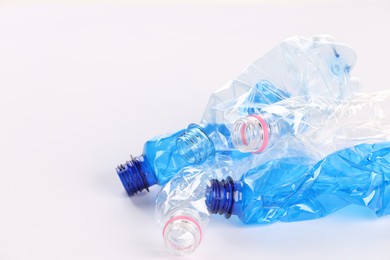 Photo of Crumpled disposable plastic bottles on white background, space for text