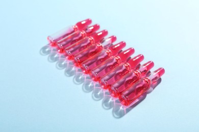 Photo of Glass ampoules with liquid on light blue background