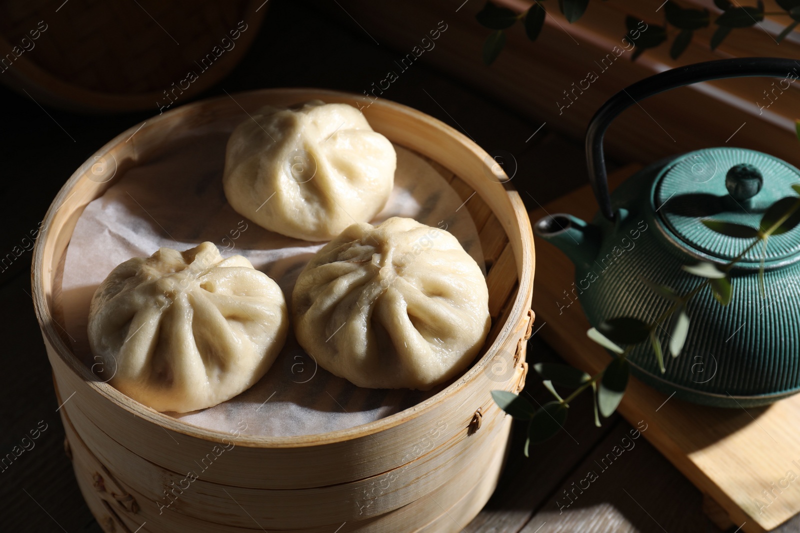 Photo of Delicious bao buns (baozi) on wooden table, closeup