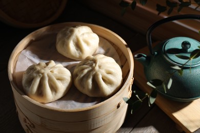 Photo of Delicious bao buns (baozi) on wooden table, closeup