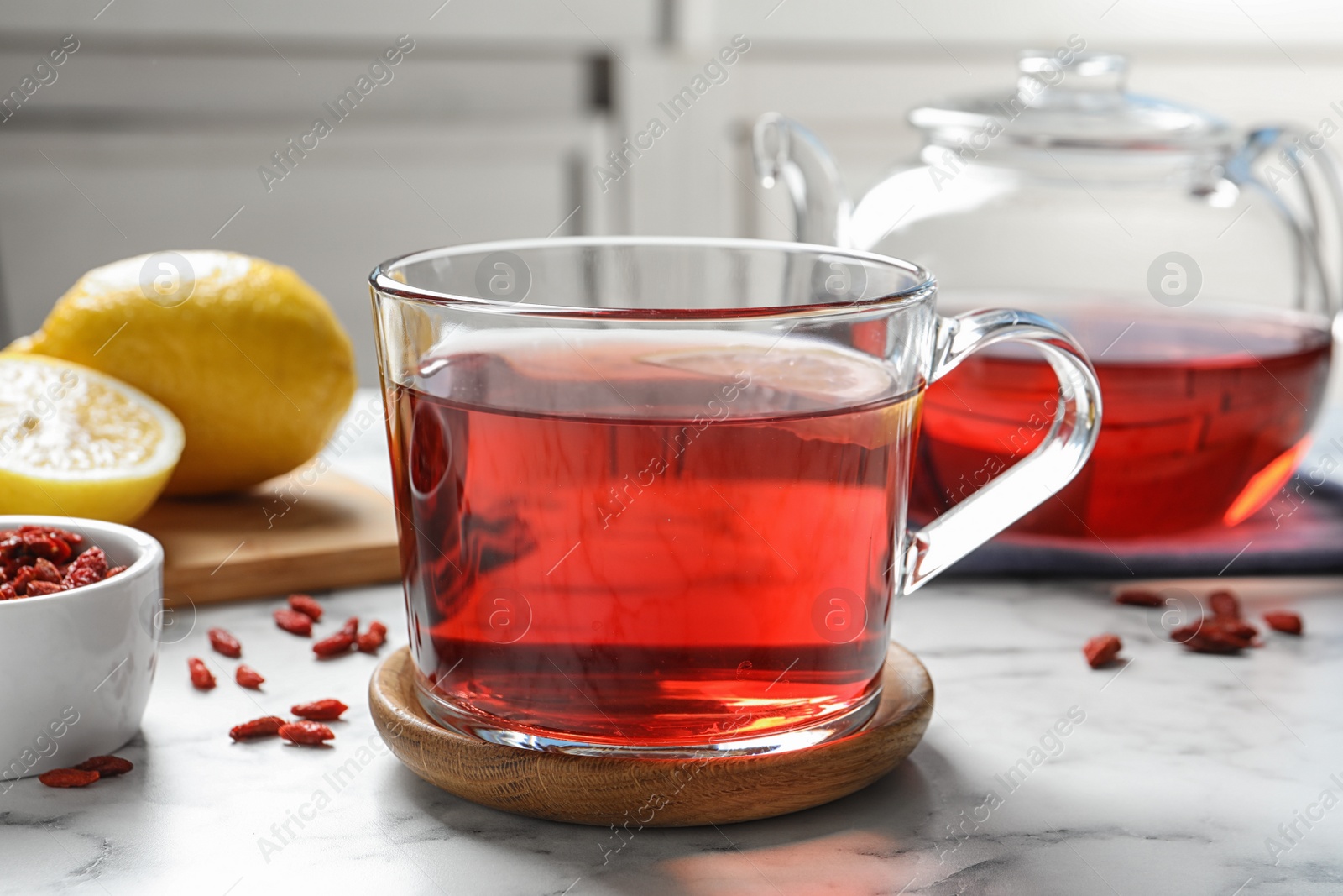 Photo of Healthy goji tea with lemon in glass cup on marble table