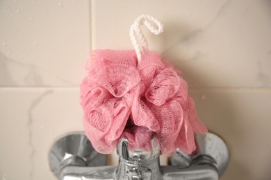 Photo of Pink shower puff on faucet in bathroom, closeup